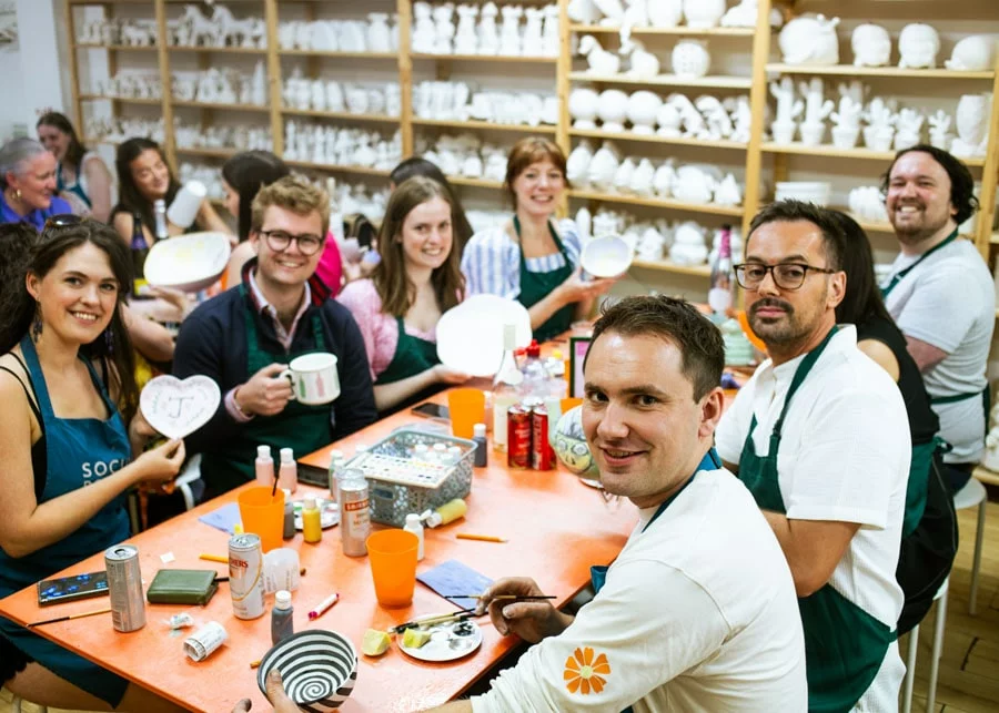 Group of people painting pottery together in a glazing studio